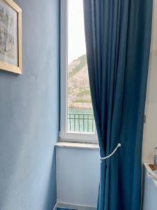 ein Fenster mit einem blauen Vorhang in einem Zimmer in der Unterkunft Il Sogno in Erchie