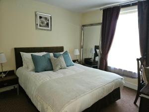 ein Schlafzimmer mit einem großen Bett mit blauen Kissen in der Unterkunft The swan at compton in Compton