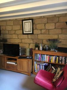 a living room with a tv and a book shelf with books at Highway Cottage in Kilburn