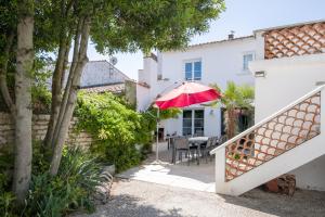 a house with a patio with a red umbrella at Maison Les Burons in Le Bois-Plage-en-Ré