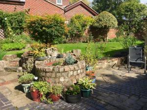 a garden with potted plants and a stone wall at Highway Cottage in Kilburn