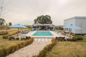 a swimming pool with two umbrellas in a field at Narbona Wine Lodge in Carmelo
