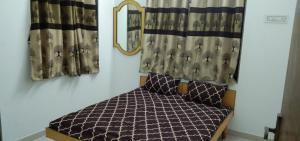a small bedroom with a bed and curtains at Madhav Homestay in Dwarka