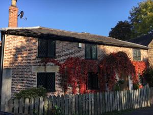 a red brick house with a wooden fence at Highway Cottage in Kilburn