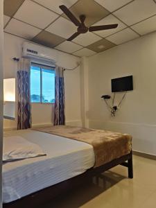 a bedroom with a bed with a ceiling fan and a window at White Shore Beach Homestay in Alleppey