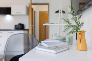 een tafel met twee boeken en een vaas met een plant bij MINT: Design Studio – Parken – Küche – WiFi in Dortmund