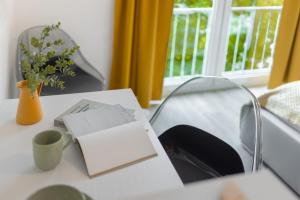 een tafel met een boek en een vaas met bloemen bij MINT: Design Studio – Parken – Küche – WiFi in Dortmund
