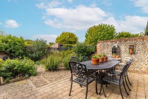 a patio with a table with chairs and plants at Nicholson Cottage in Happisburgh