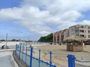 uma praia com um edifício e uma cerca azul em Appartement IJsselmeer Makkum strand em Makkum