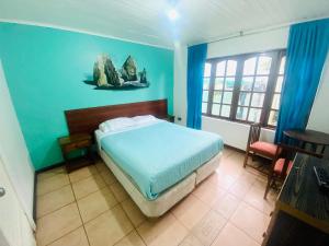 1 dormitorio con cama y pared azul en Hostel Costa Morena, en Constitución