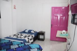 um quarto com uma cama e uma porta rosa em RIO Colors - Hospedaje em Barrancabermeja