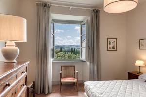 a bedroom with a bed and a window and a chair at Casale di Villore in Poggibonsi
