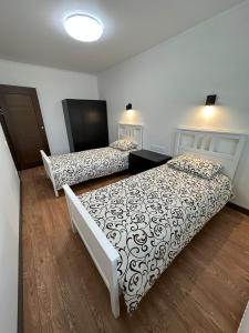 two beds in a room with wooden floors at Swan City Family Apartment in Gulbene