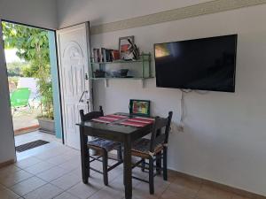 een eettafel met een flatscreen-tv aan de muur bij Studio un nid in Douliana