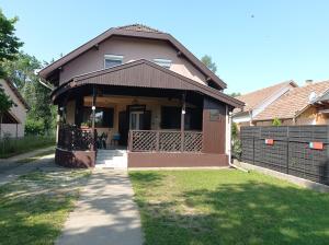 ein Haus mit einer überdachten Veranda auf einem Rasen in der Unterkunft Partifecske Vendégház in Tiszafüred