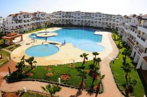 eine Luftansicht auf einen großen Pool in einem Resort in der Unterkunft Bel appartement estival 2 chambres à Garden beach in Sidi Rahal