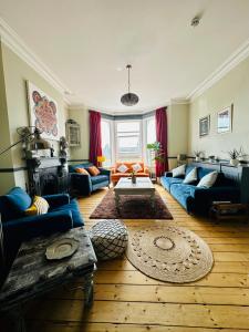 una sala de estar con sofás azules y una mesa. en Zen House By The Sea In Margate en Kent