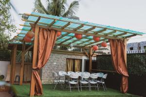 a wooden pergola with white chairs and a table at Brynx Haven - Adenta, Accra in Accra