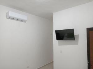 TV de pantalla plana en una pared blanca en una habitación en Casa Tauch en Cancún