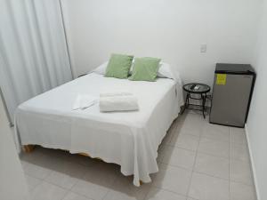 ein weißes Bett mit grünen Kissen darüber in der Unterkunft Casa Tauch in Cancún