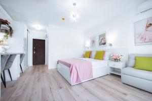 a white bedroom with a bed and a couch at Studio Vladut in Saturn