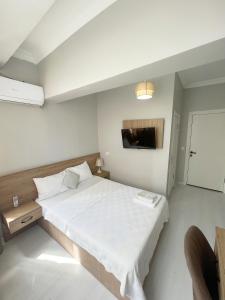 a white bedroom with a large bed and a tv at Karhal Hotel in Edirne