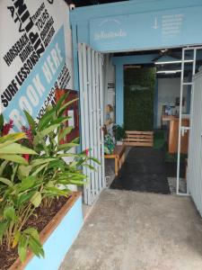 una entrada a un edificio con un banco y plantas en La Hacienda Rooms & Food, en Jacó