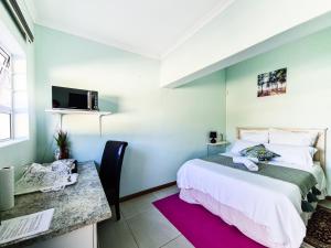 a bedroom with a bed and a desk and a tv at H G Deluxe Guest suites in East London