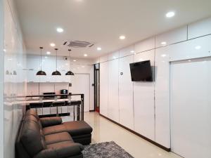 een woonkamer met een leren bank en een televisie bij NK Guesthouse 1 in Klong Toi