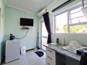 a kitchen with a refrigerator and a tv on the wall at H G Deluxe Guest suites 1 in East London