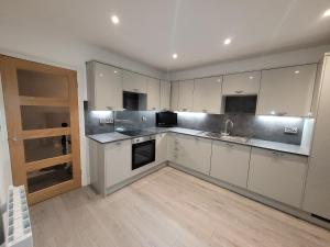 a kitchen with white cabinets and a wooden floor at Snowdon view, steam railway & Portmeirion nearby in Mynfford +7 photos