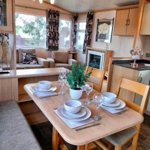 een tafel met borden en wijnglazen in de keuken bij Cosy & Beautiful Charrot Caravan in Steeple