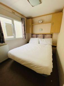 a bedroom with a large white bed with a window at Cosy & Beautiful Charrot Caravan in Steeple