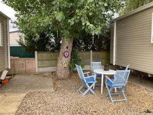 a table and chairs sitting next to a tree at Cosy & Beautiful Charrot Caravan in Steeple