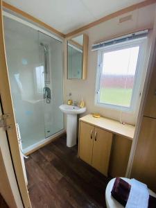 a bathroom with a glass shower and a sink at Cosy & Beautiful Charrot Caravan in Steeple