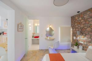 1 dormitorio con pared de piedra, cama y espejo en Loukas & Emma Houses, en Perissa
