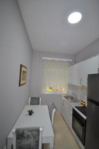 a white kitchen with a table and a sink at Little Cozy Apartment 1 in Sarandë