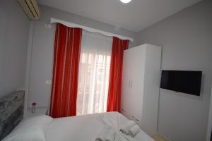 a bedroom with a bed and a window with red curtains at Little Cozy Apartment 1 in Sarandë