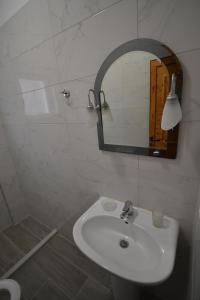 a white bathroom with a sink and a mirror at Little Cozy Apartment 1 in Sarandë +5 photos