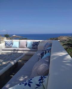 un sofá blanco con almohadas azules y blancas sentadas en una cornisa en SerenSea Bliss, Naousa, Kythnos en Kíthnos