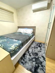a small bedroom with a bed and a rug at Cozy Condo in Pasig City- Bali Oasis 2 in Manila