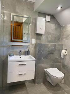 La salle de bains est pourvue d'un lavabo blanc et de toilettes. dans l'établissement Midom, à Małdyty