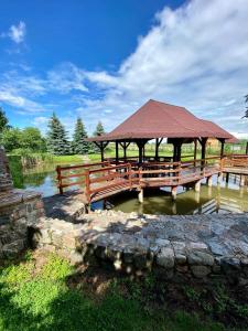 a wooden bridge with a gazebo next to a pond at Midom in Małdyty