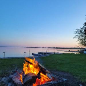 a fire pit in a field next to a body of water at Lakefront Cottage in Sturgeon Falls