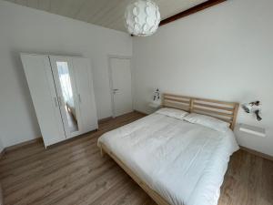 Habitación blanca con cama y lámpara de araña. en CASA n 61 en Dervio