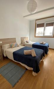- une chambre avec 2 lits avec des draps bleus et 2 fenêtres dans l'établissement A Segunda Ronda, à Melide