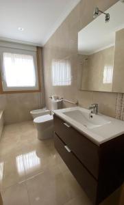 ein Badezimmer mit einem Waschbecken, einem WC und einem Spiegel in der Unterkunft A Segunda Ronda in Melide