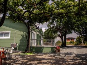 een groen huis met een veranda en een tafel en stoelen bij New Village Home, Near to Beaches-Natural Zone in Ortaca