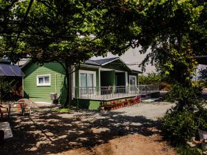 een groen huis met een veranda en een boom bij New Village Home, Near to Beaches-Natural Zone in Ortaca