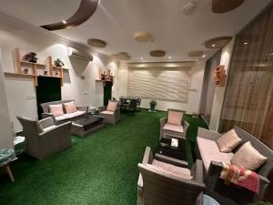 ein Wohnzimmer mit Sofas, Stühlen und grünem Teppich in der Unterkunft الارتقاء الفاخرة المخدومة in Abha